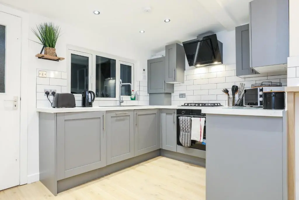 a kitchen with white cabinets and a sink at mySTAYINN Tomnahurich 3 Bedroom House in Inverness