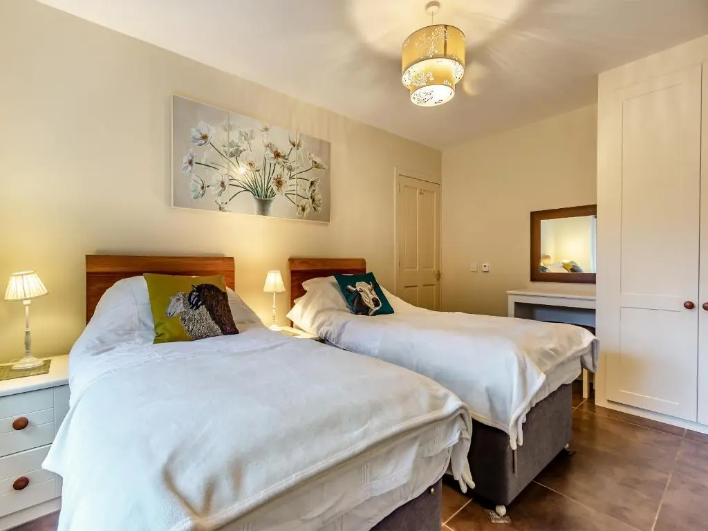 a bedroom with two beds and a mirror at Allt Bronach - Ukc5763 in Laggan