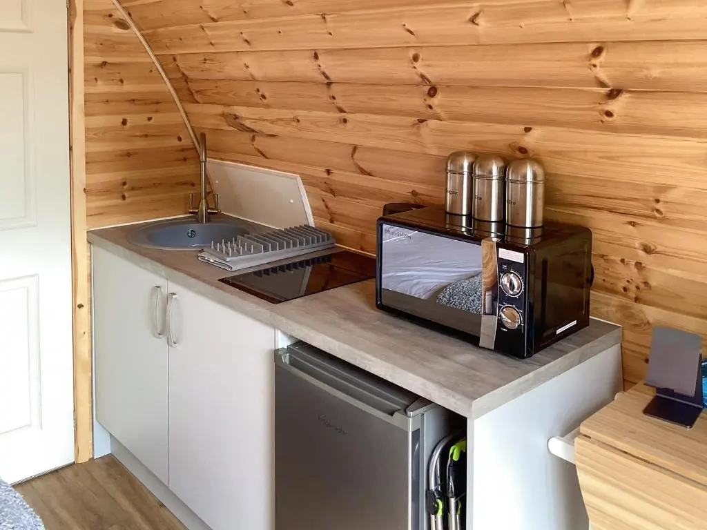a small kitchen with a microwave and a sink at The Dalmore Pod in Alness