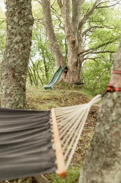 a hammock in a wooded area with trees at Balnagowan Cottage in Nethy Bridge