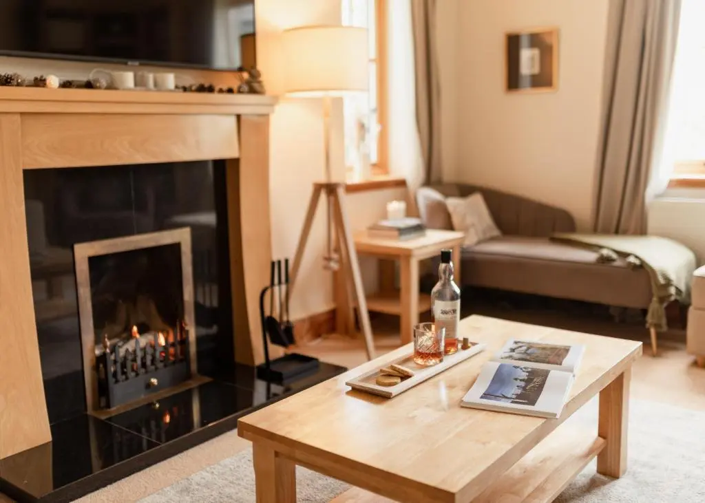 a living room with a fireplace and a coffee table at Balnagowan Cottage in Nethy Bridge