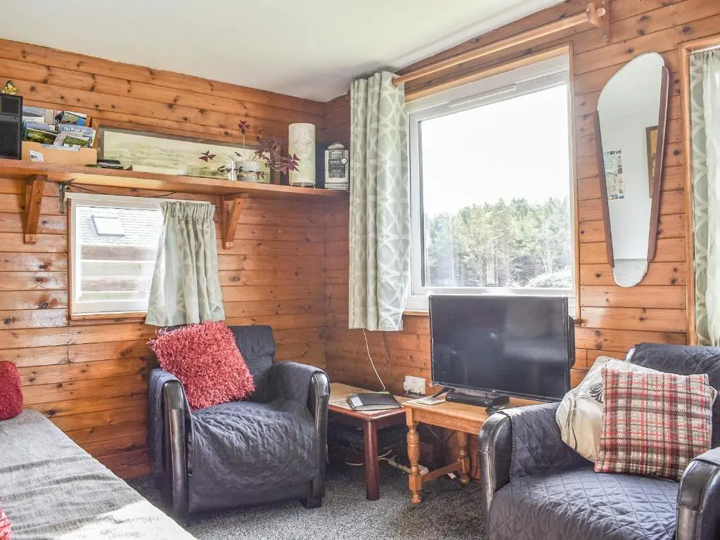 a living room with two chairs and a television at The Chalet - Ukc5786 in Nethy Bridge