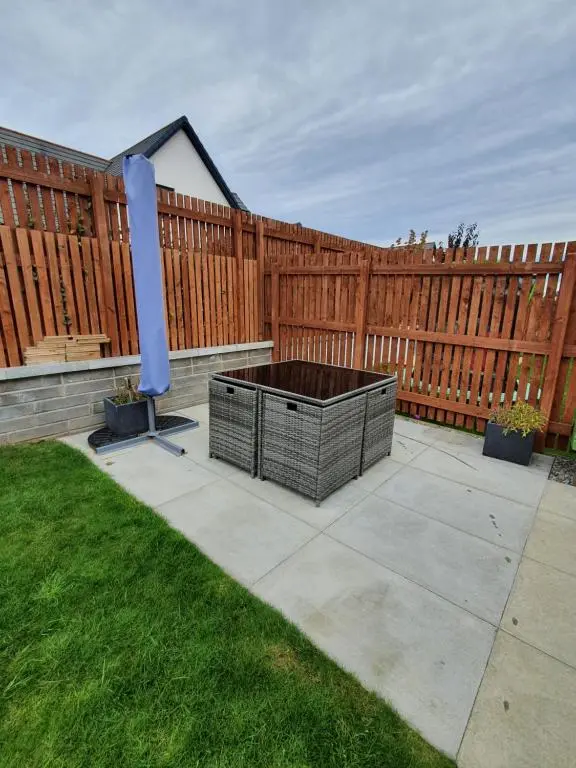 a patio with a fire pit in front of a wooden fence at The White House in Elgin