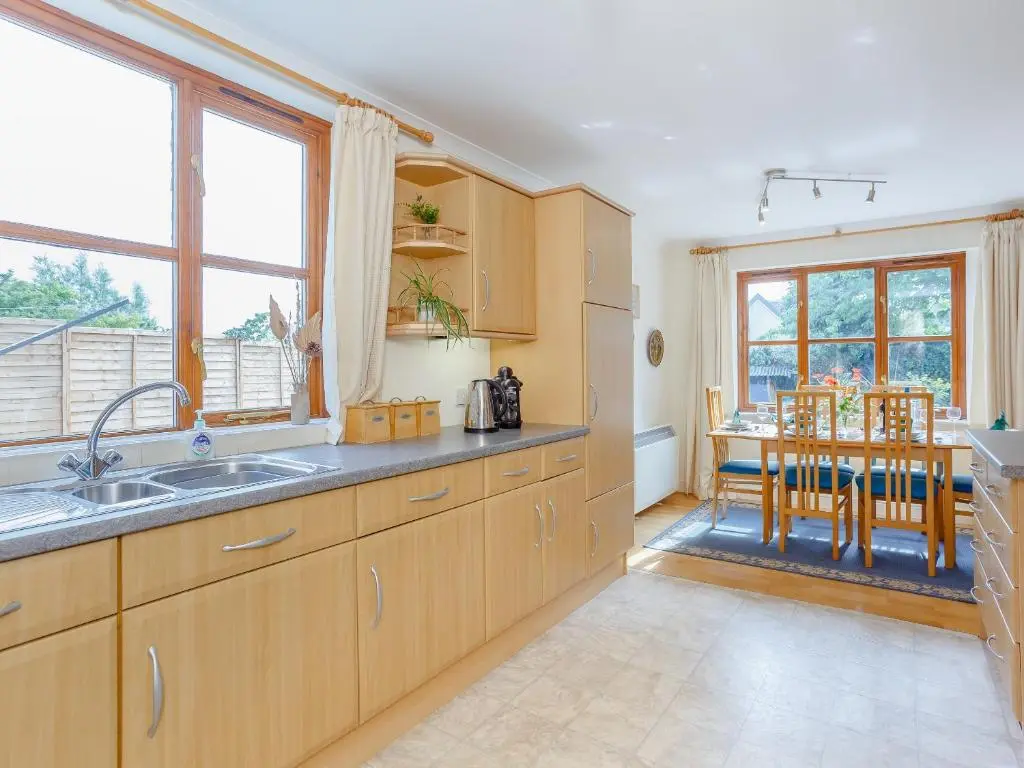 a kitchen with wooden cabinets and a table with chairs at Caldon Cottage in Cromarty