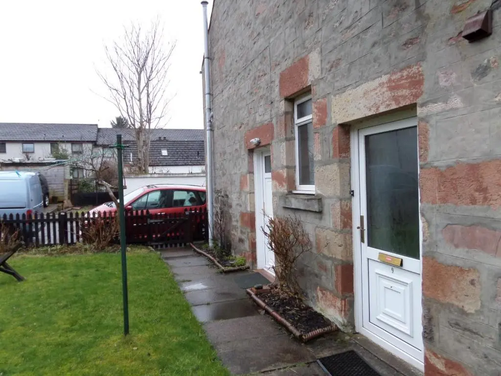 a brick house with a white door and a yard at Jane's Cottage Free Parking in Inverness