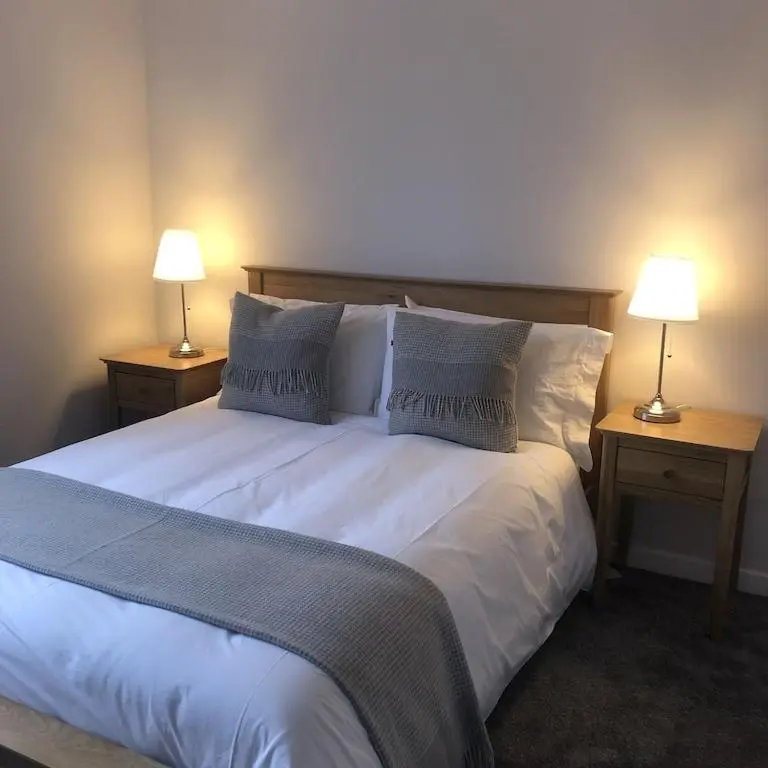 a bedroom with a large white bed with two lamps at Foinaven House in Ullapool