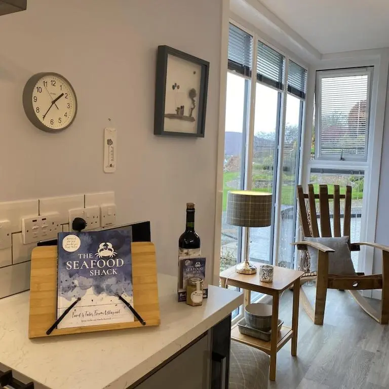 a kitchen with a table with a bottle of wine and a clock at Foinaven House in Ullapool