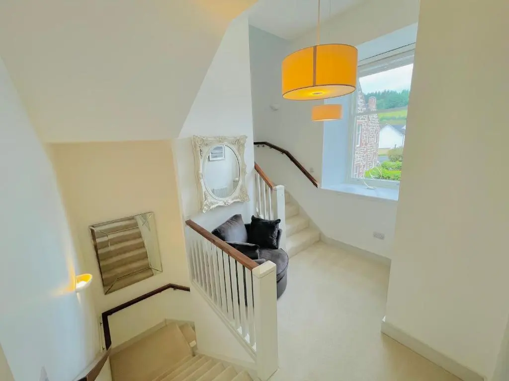 a black cat sitting on a chair in a stair case at Great Glen Townhouse Inverness - Entire 3 Story Townhouse in Inverness