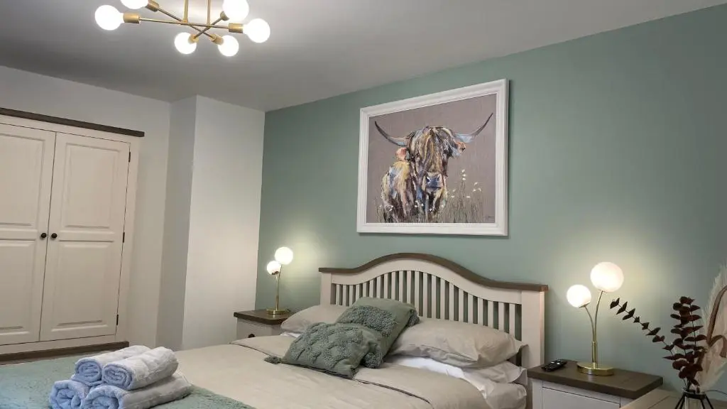 a bedroom with a bed and a picture of a cow at The Forge by Caithness Luxury Apartments NC500 - Elegant Luxury Apartment with Bike store - Sleeps 4 in Wick
