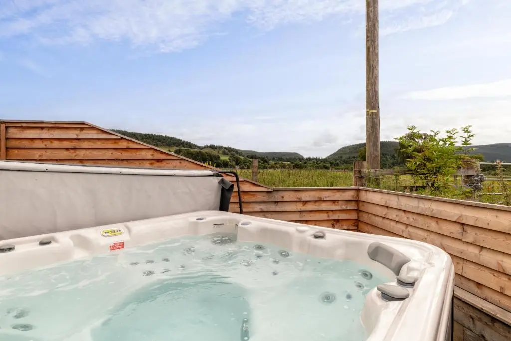 a jacuzzi tub on a balcony with a view at Alba - Charming boutique forest view cabin with hot tub in Ballater in Ballater