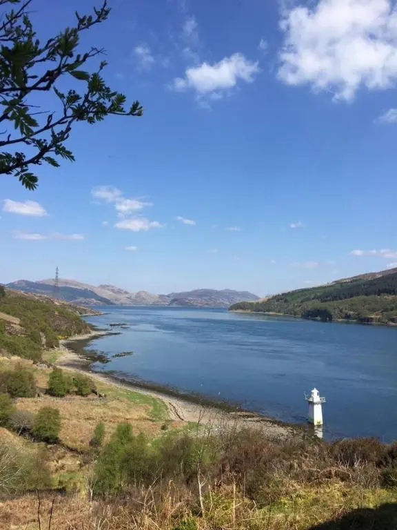 a large body of water with a white lighthouse on the shore at Torgoyle Cottage in Inverness