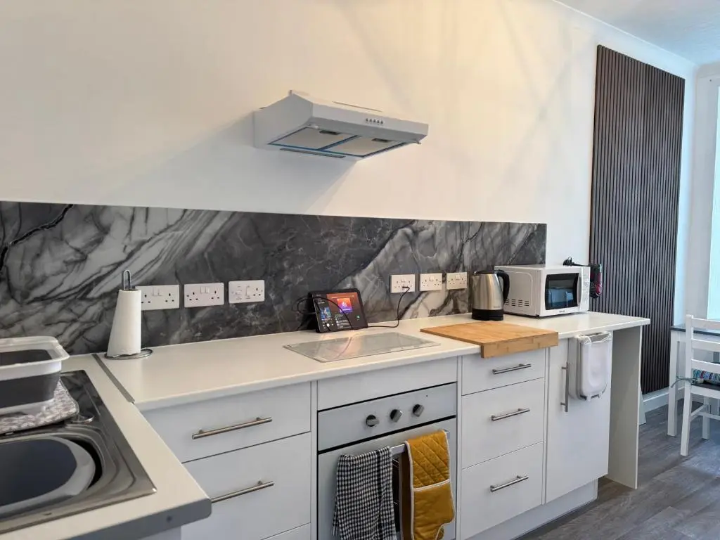 a kitchen with a stove and a sink and a microwave at Helens Lybster cosy cottage on NC500 in Lybster