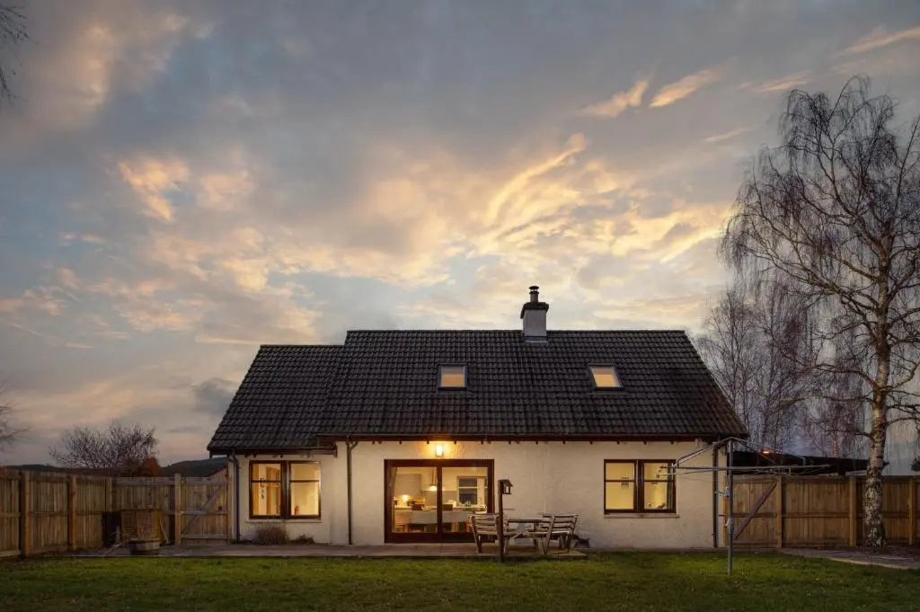 a small white house with a sunset in the background at Anne's Place in Boat of Garten