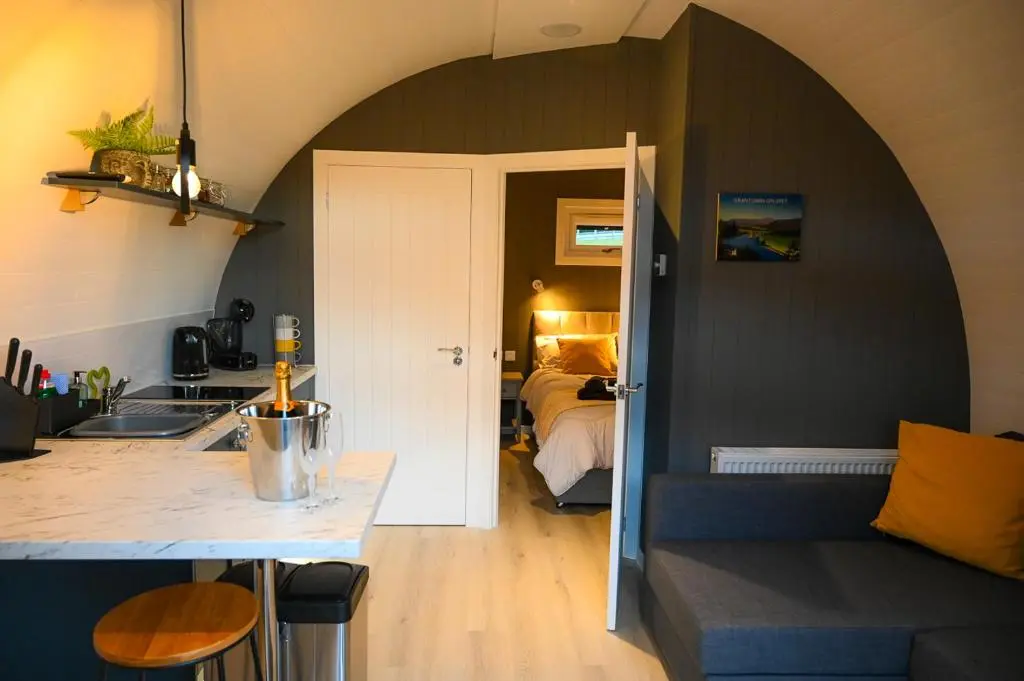 a kitchen and living room with a couch and a bed at Newmore Highland Pods with Hot Tubs on NC500 in Invergordon