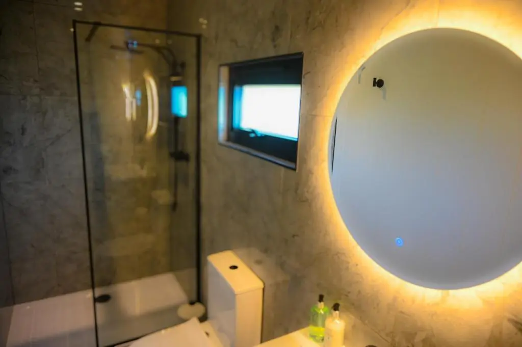 a bathroom with a mirror and a sink and a shower at Newmore Highland Pods with Hot Tubs on NC500 in Invergordon