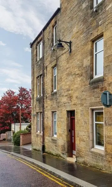 a brick building with a red door on a street at Stephen's Street Apartment, Inverness City Centre in Inverness