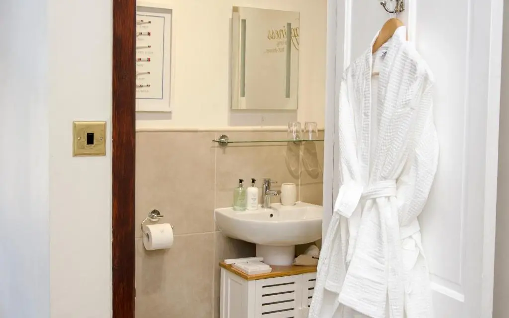 a bathroom with a sink and a white robe at Strathallan Bed and Breakfast in Grantown on Spey