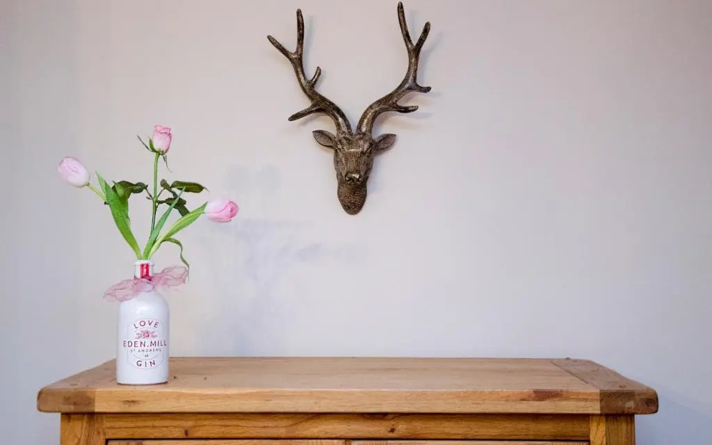 a vase with pink flowers and a deer head hanging on a wall at Strathallan Bed and Breakfast in Grantown on Spey