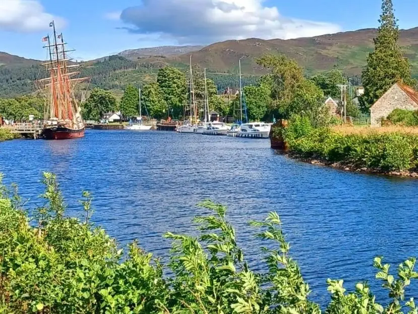 a river with boats on it with mountains in the background at Erraid Lodge in Fort Augustus