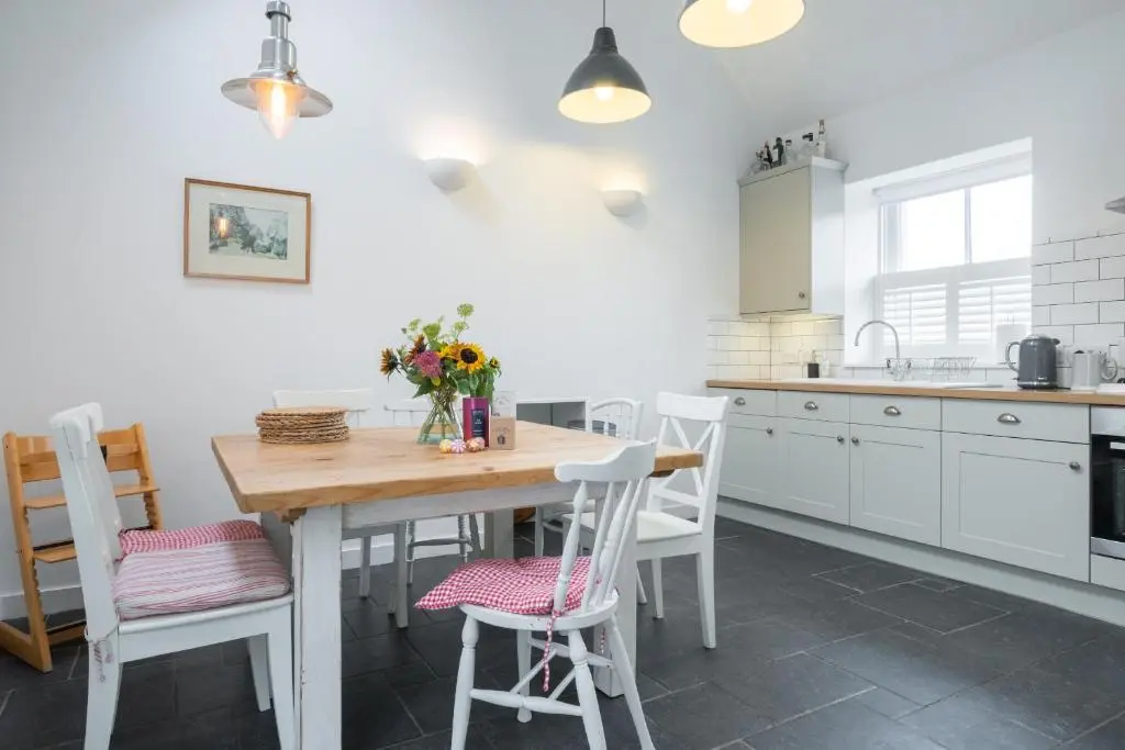 a kitchen with a wooden table and white cabinets at Seaside cottage on Moray coast in Portknockie