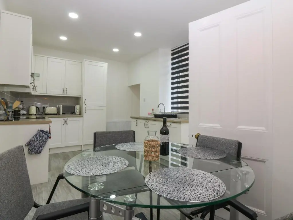 a kitchen with a glass table and chairs in a kitchen at RockStar Cottage in Macduff
