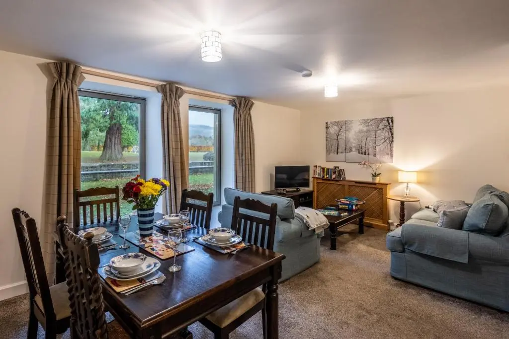 a living room with a table and a couch at Raven Wing Apartments - Highland Club Scotland in Fort Augustus