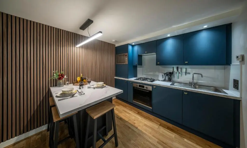 a kitchen with blue cabinets and a counter top at Raven Wing Apartments - Highland Club Scotland in Fort Augustus