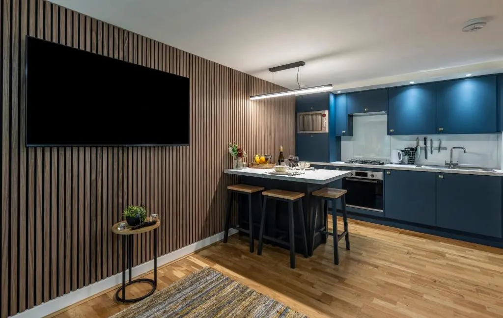 a kitchen with a bar with a tv on the wall at Raven Wing Apartments - Highland Club Scotland in Fort Augustus