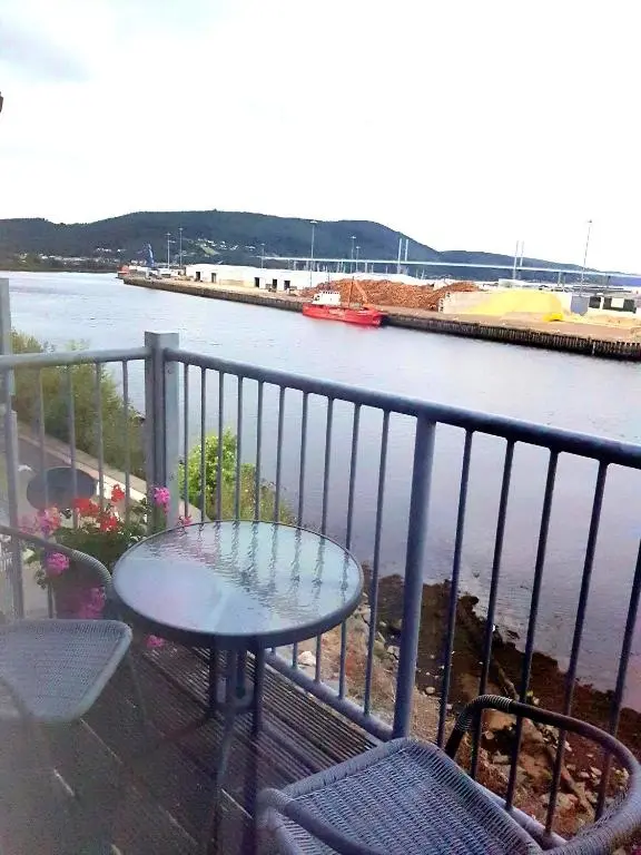 a table and chairs on a balcony overlooking a river at Aber Holiday Rentals in Inverness