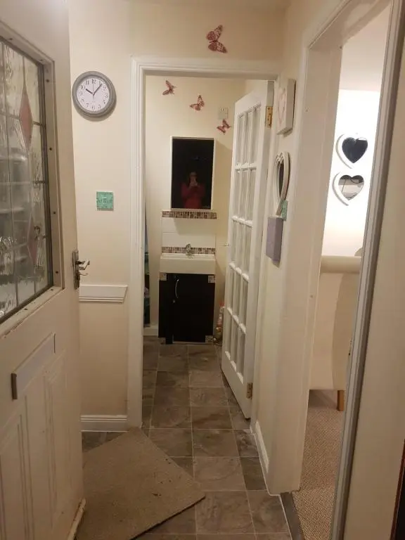a hallway with a door and a clock on the wall at Nannys tiny hoose in Inverness