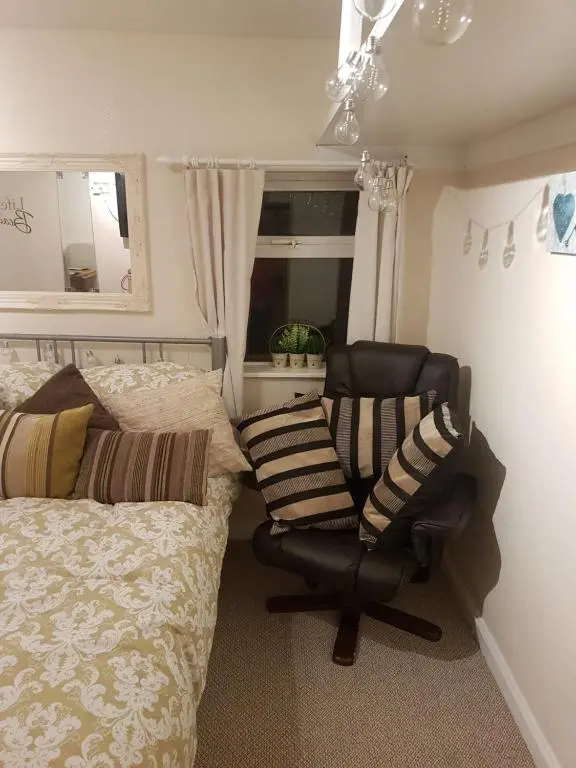 a bedroom with a bed and a chair and a mirror at Nannys tiny hoose in Inverness