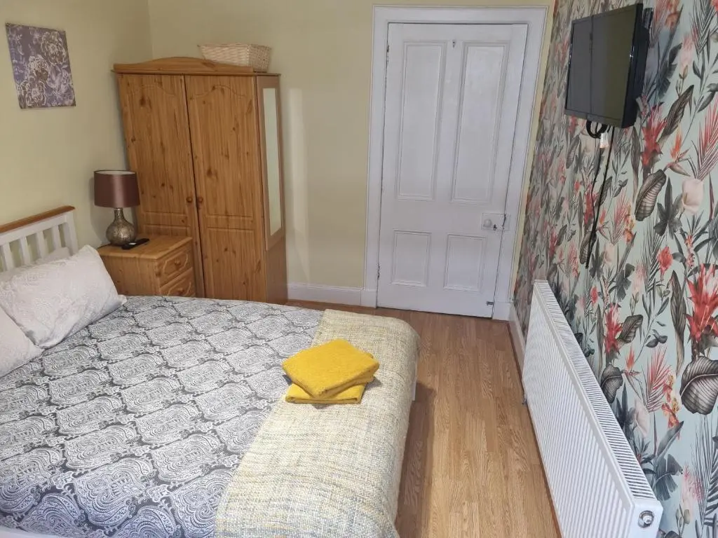 a bedroom with a bed and a yellow towel on a couch at Nanny Bambi's highland hoose in Inverness