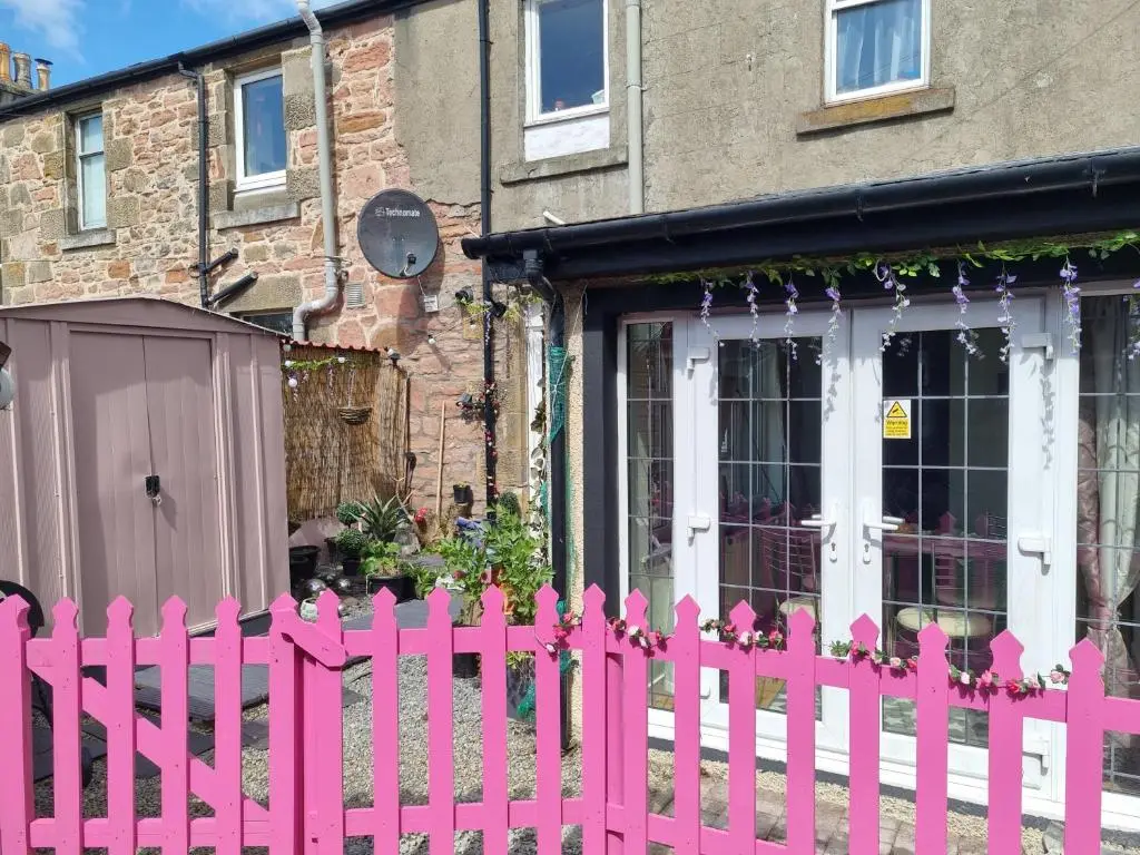 a pink fence in front of a house at Nanny Bambi's highland hoose in Inverness