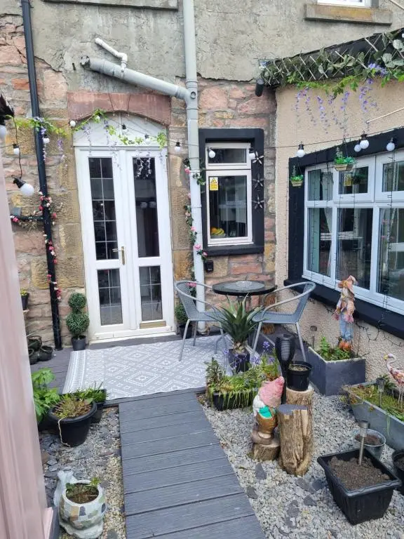 a patio with a table and chairs in front of a building at Nanny Bambi's highland hoose in Inverness