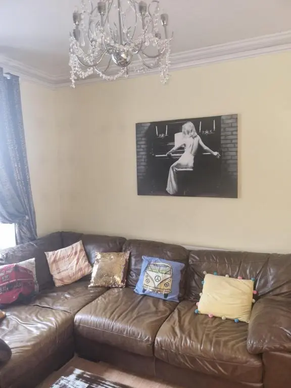a living room with a brown leather couch and a chandelier at Nanny Bambi's highland hoose in Inverness