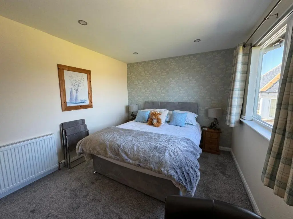 a bedroom with a bed with a dog sitting on it at Drumhead Cottage Finzean, Banchory Aberdeenshire Self Catering with Hot Tub in Finzean