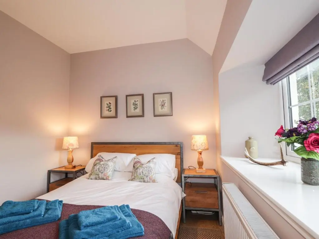 a bedroom with a bed and two lamps and a window at Bonnach in Muir of Ord
