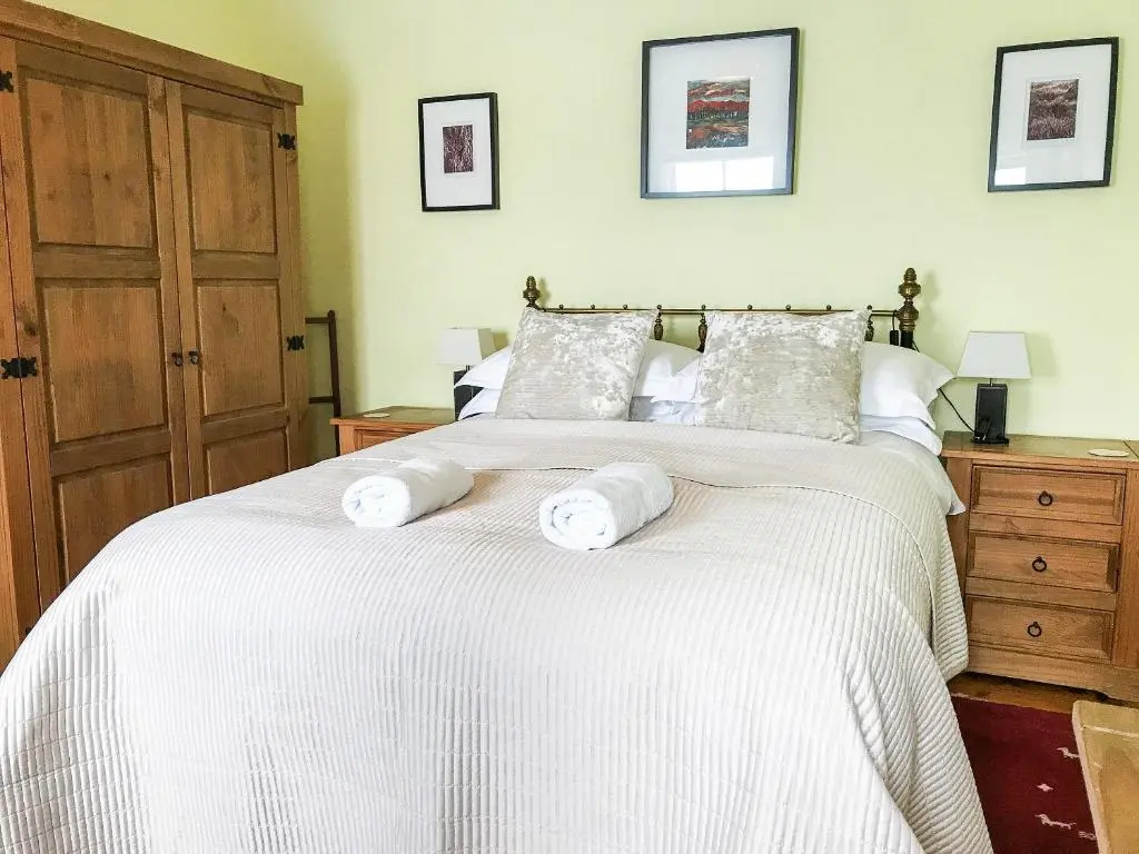 a bedroom with a large white bed with towels on it at Tigh Beag in Newtonmore