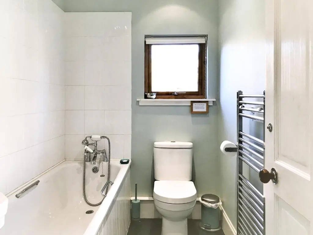 a bathroom with a toilet and a tub and a window at Tigh Beag in Newtonmore