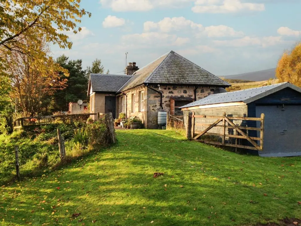 an old stone house with a fence and a yard at Tigh Beag in Newtonmore