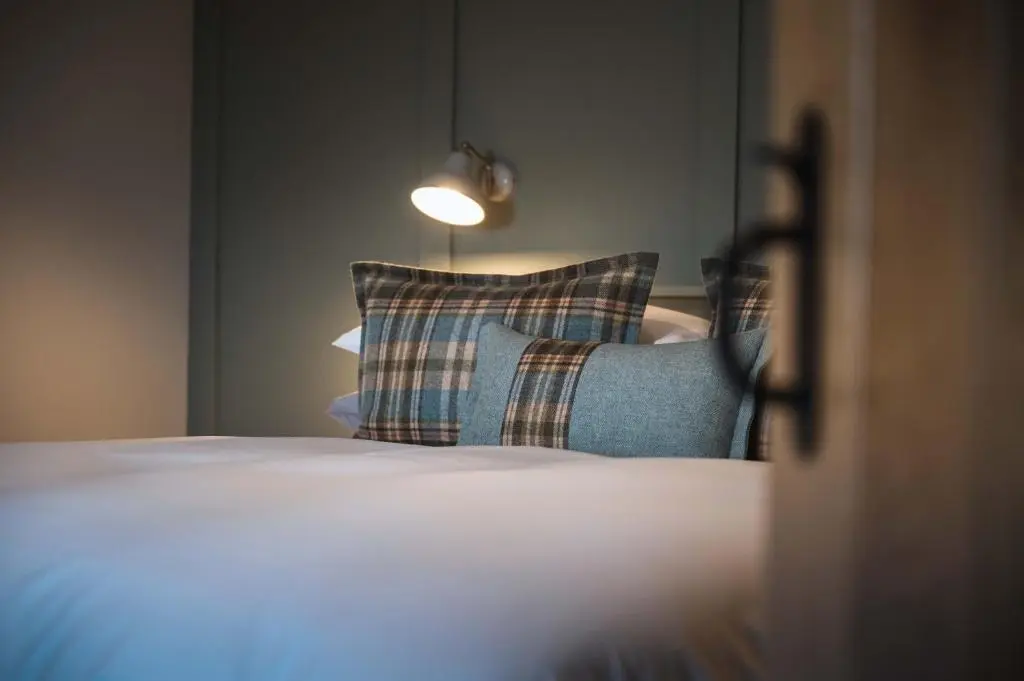 a bedroom with a bed with pillows and a lamp at Drumdry in Wick