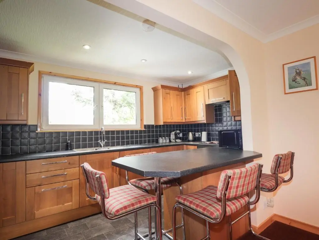 a kitchen with a island with bar stools at Garden Lodge in Muir of Ord