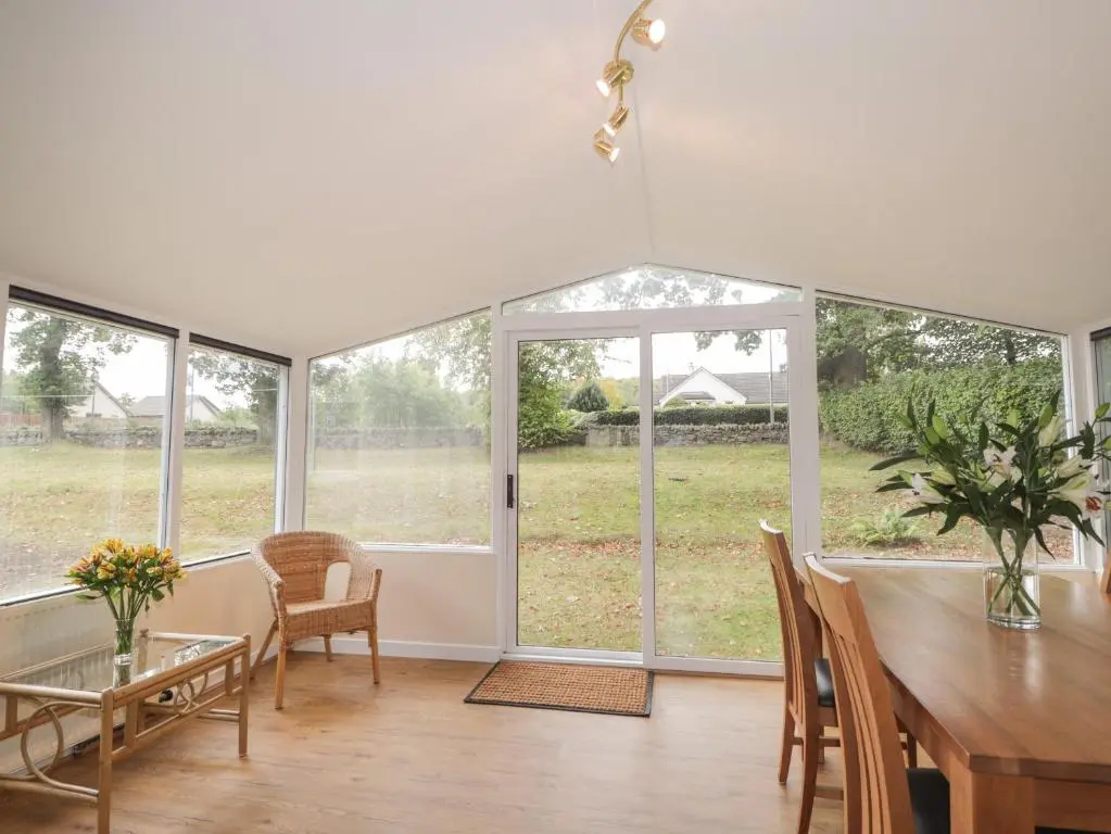 a dining room with a table and chairs and windows at Garden Lodge in Muir of Ord
