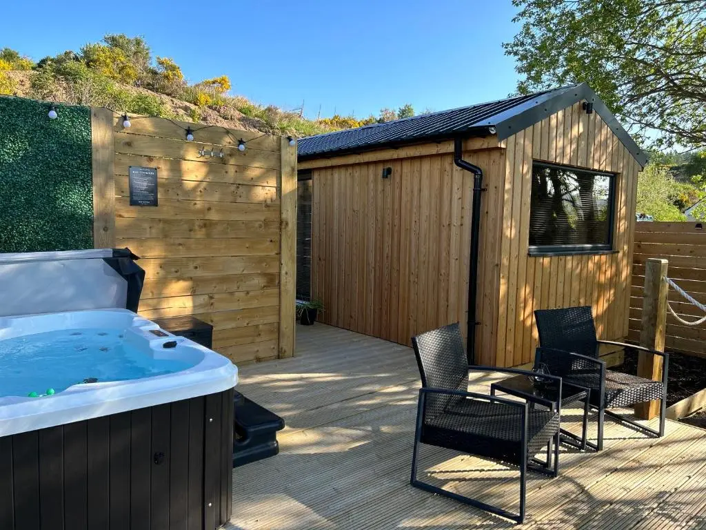 a hot tub on a deck next to a building at River Huts with Private Hot Tubs in Inverness