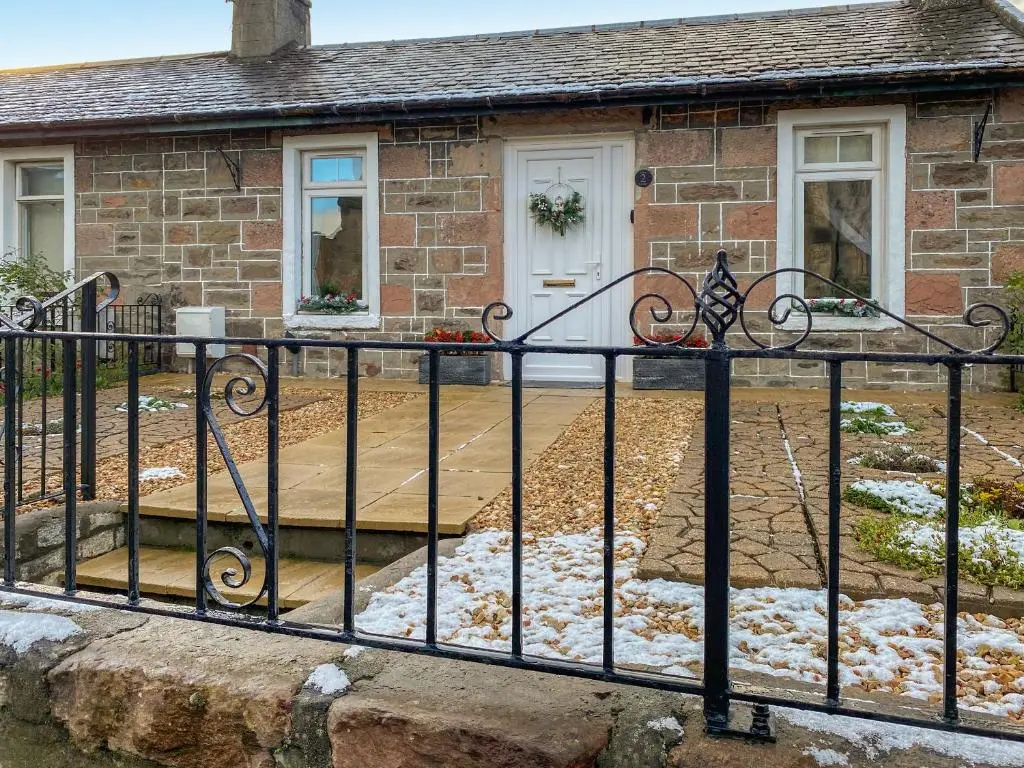 a house with a black fence in front of it at Dove Cottage in Inverness