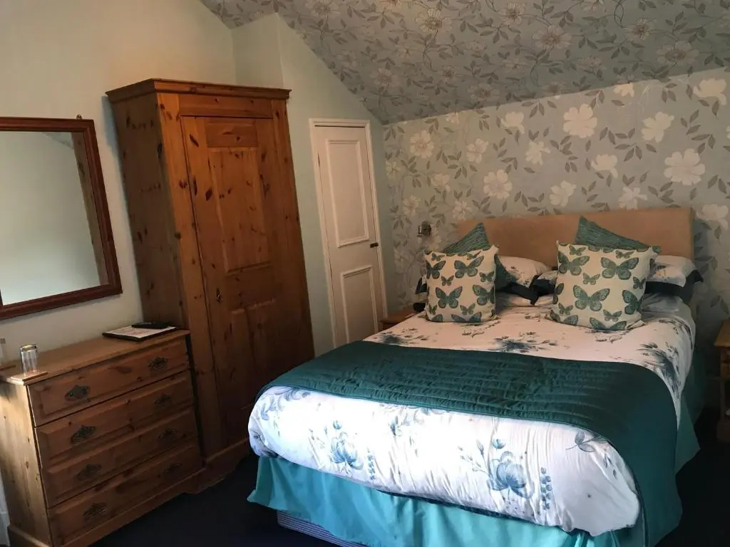 a bedroom with a bed with a dresser and a mirror at Moyness House in Inverness