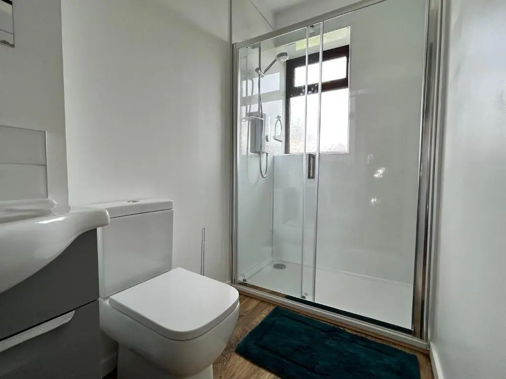 a white bathroom with a toilet and a shower at Lottie\u2019s Cottage, Rhynie, Aberdeenshire in Rhynie