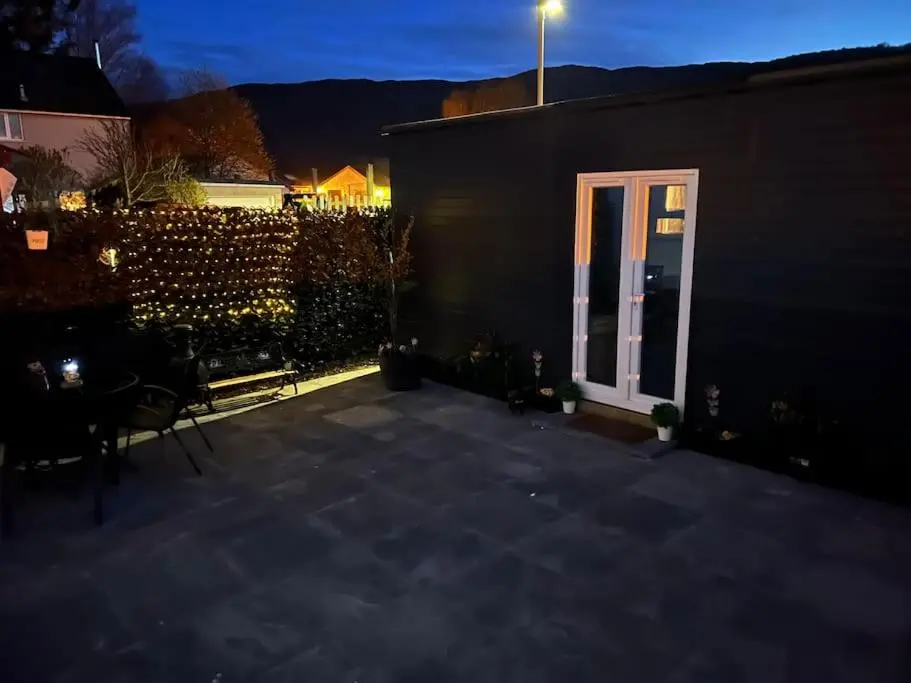 a patio with a door and a fence at night at Craigellachie Cabin in Aviemore