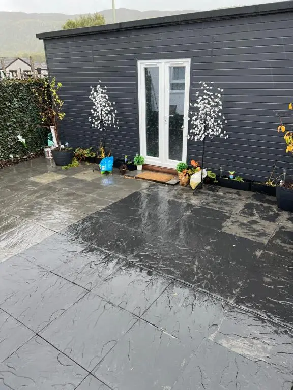 a black house with a concrete driveway in front of it at Craigellachie Cabin in Aviemore