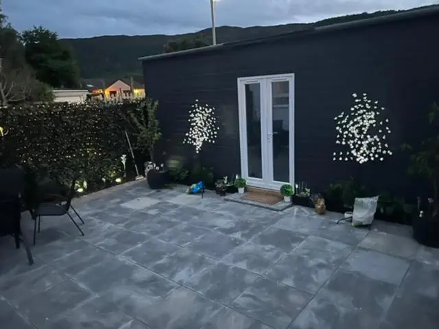 a patio with a building and a door with lights at Craigellachie Cabin in Aviemore